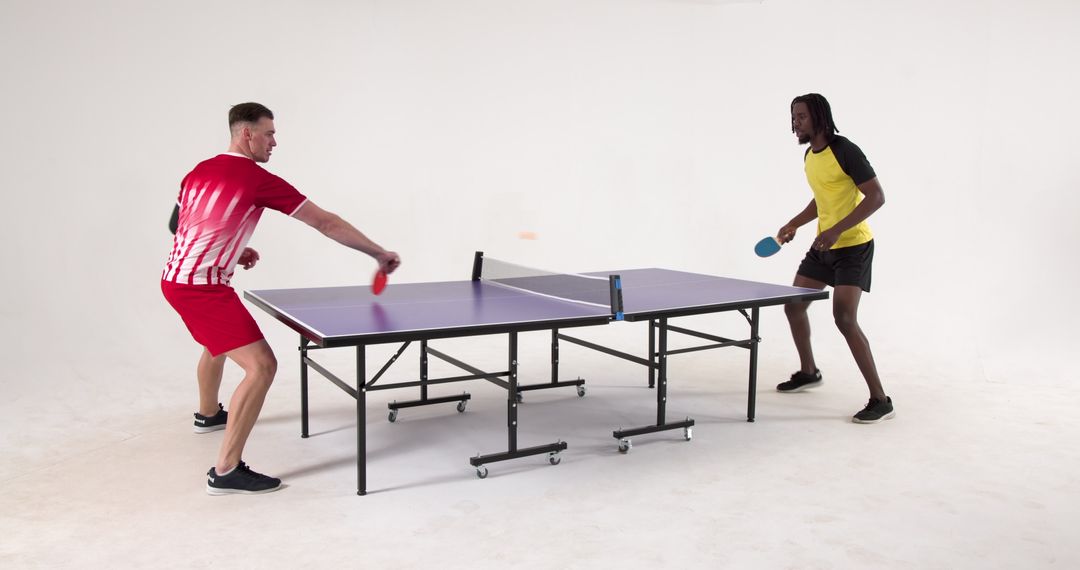 Two Diverse Friends Enjoying Competitive Table Tennis in Modern Studio