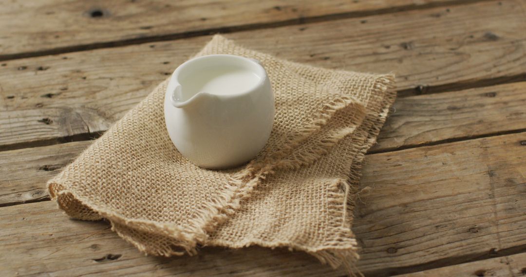 Rustic Ceramic Milk Jug on Wooden Table and Burlap Cloth - Free Images, Stock Photos and Pictures on Pikwizard.com