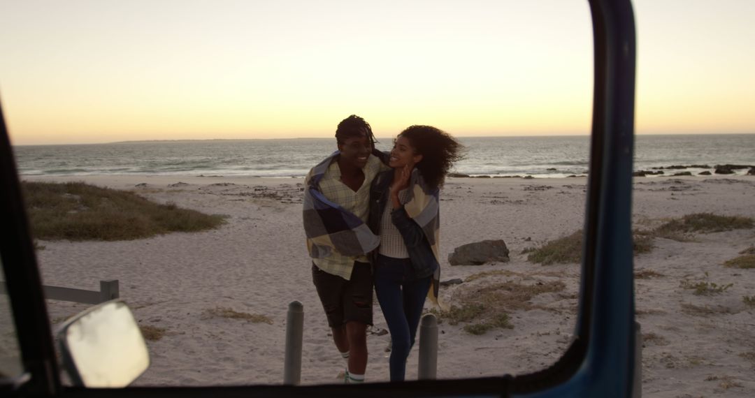 African American couple enjoys a romantic beach walk under a blanket at sunset. - Free Images, Stock Photos and Pictures on Pikwizard.com