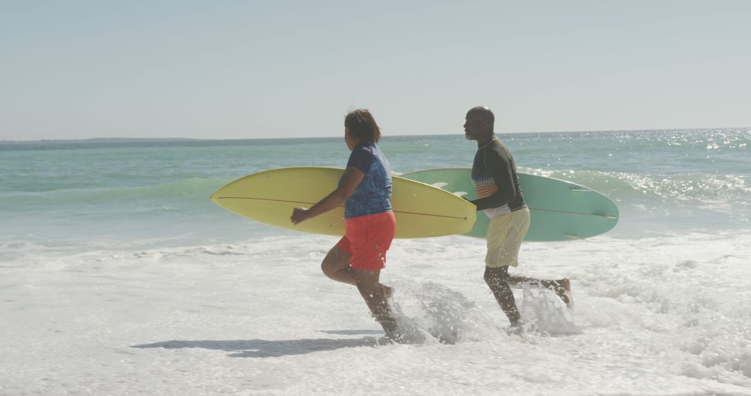 Surfing Couple Entering Waves on Sunny Beach - Free Images, Stock Photos and Pictures on Pikwizard.com