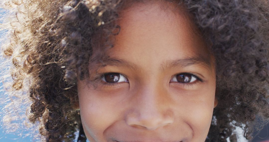 Close-Up Portrait of Smiling Young Child with Curly Hair - Free Images, Stock Photos and Pictures on Pikwizard.com