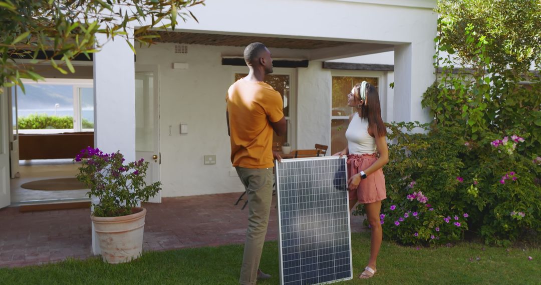 Diverse Couple Discussing Installation of Solar Panel Outside Modern Home