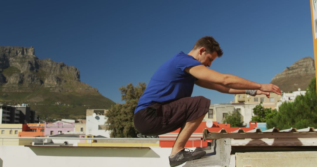 Man Performing Parkour Jump in Urban Area with Mountain Background - Free Images, Stock Photos and Pictures on Pikwizard.com