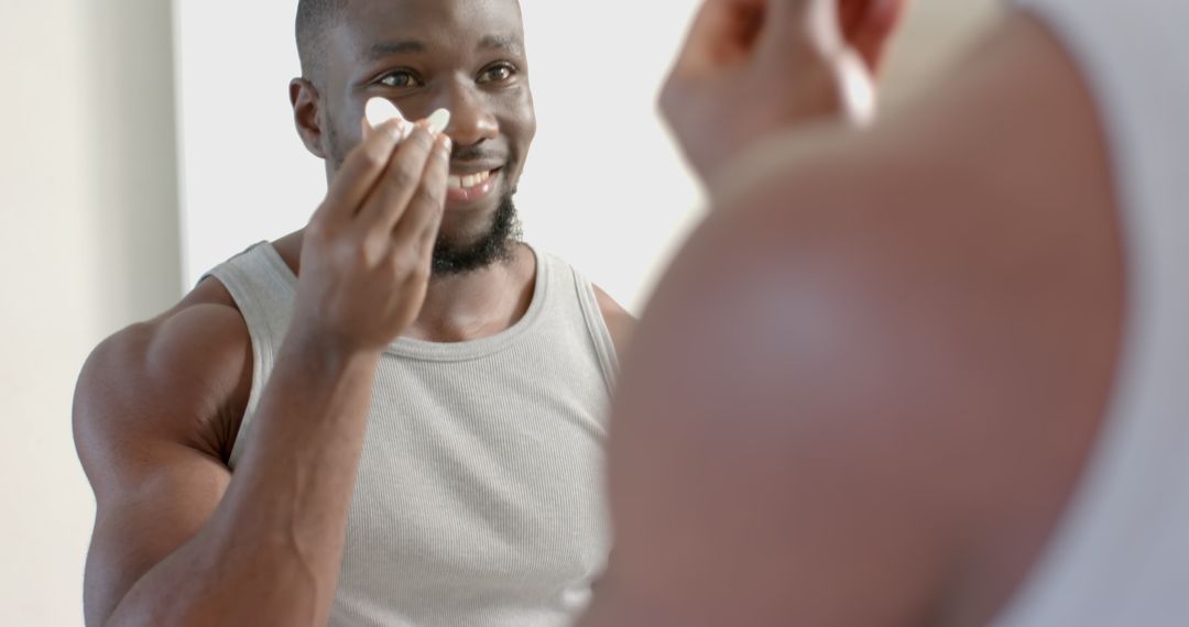 Man Practicing Skincare Routine in Front of Mirror