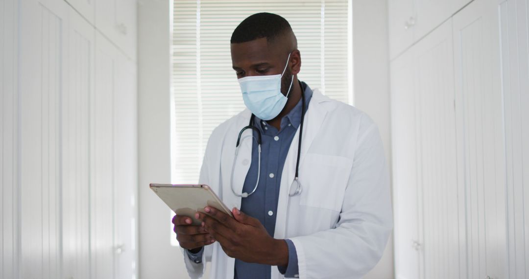 Healthcare Professional Wearing Mask Using Tablet in Medical Facility - Free Images, Stock Photos and Pictures on Pikwizard.com