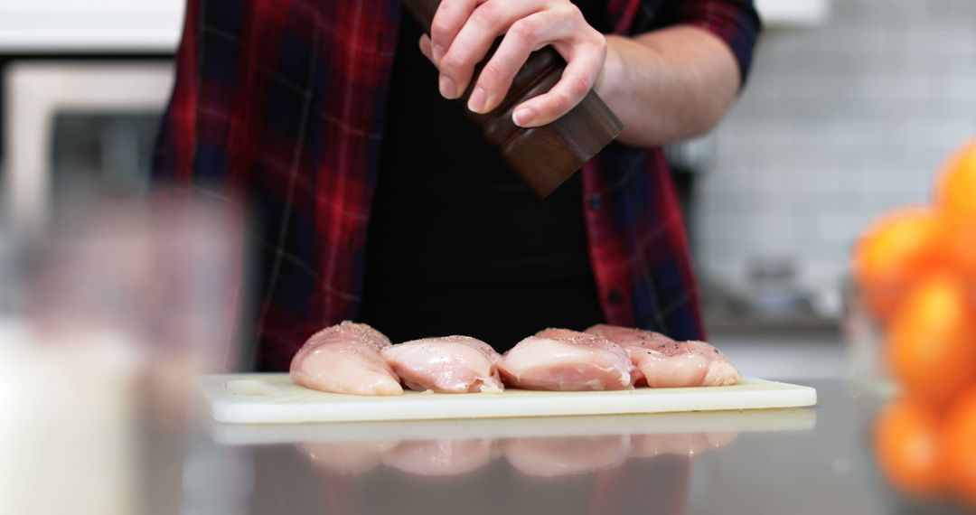 Person seasoning raw chicken breasts on kitchen counter - Free Images, Stock Photos and Pictures on Pikwizard.com