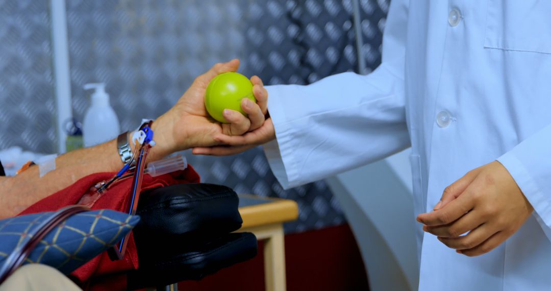 Doctor Assisting Patient During Blood Donation with Green Stress Ball - Free Images, Stock Photos and Pictures on Pikwizard.com