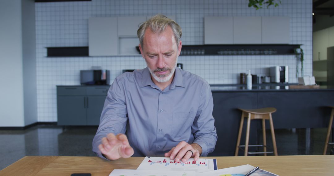Senior Businessman Analyzing Documents in Modern Office Kitchen