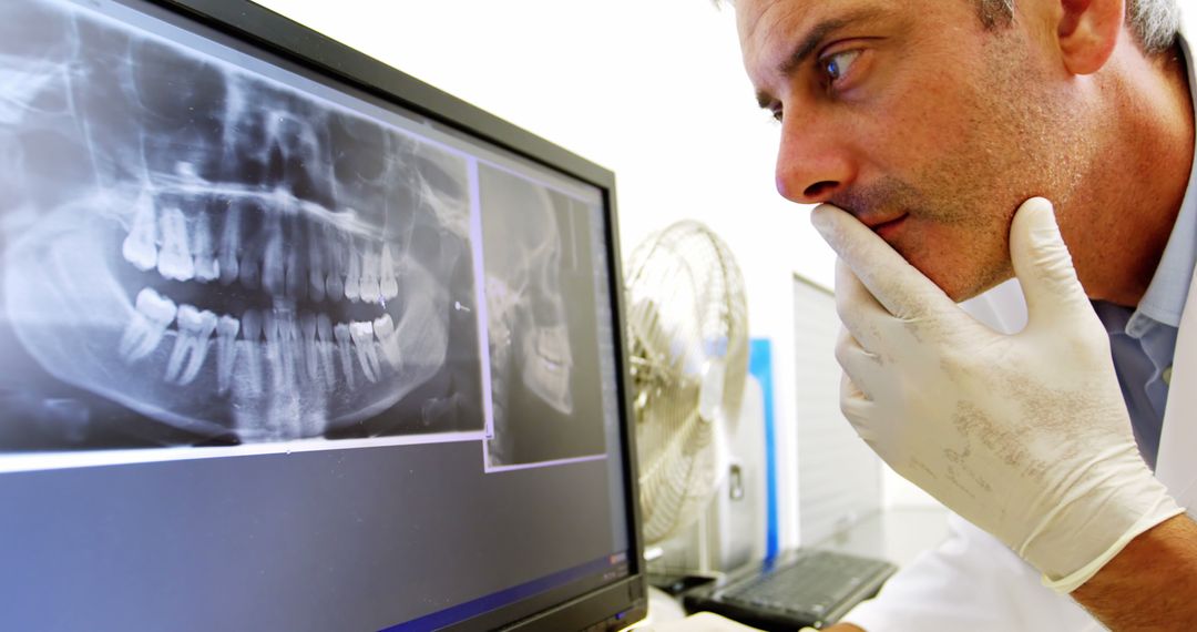 Dentist Analyzing Dental X-Ray on Monitor in Modern Clinic - Free Images, Stock Photos and Pictures on Pikwizard.com