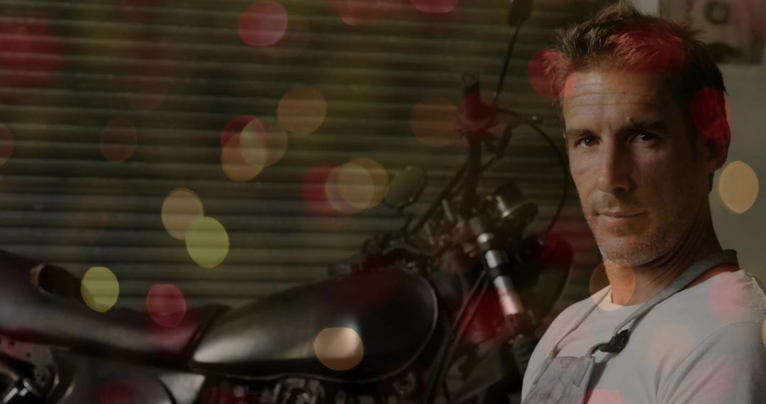 Middle-aged mechanic inspecting custom motorcycle in moody garage with bokeh lights