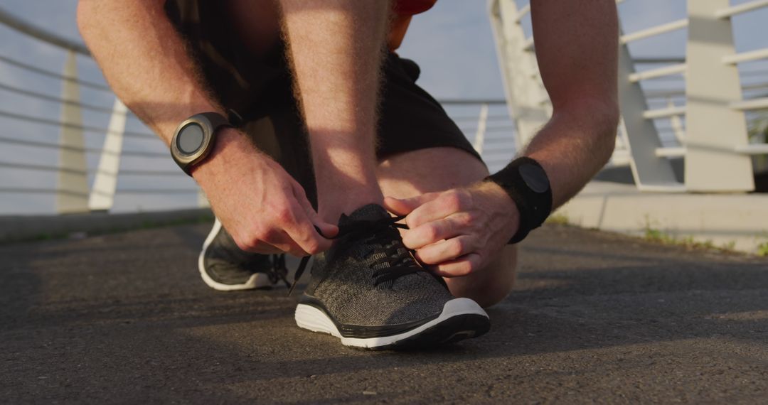 Male Runner Tying Running Shoes on Urban Bridge at Sunrise - Free Images, Stock Photos and Pictures on Pikwizard.com