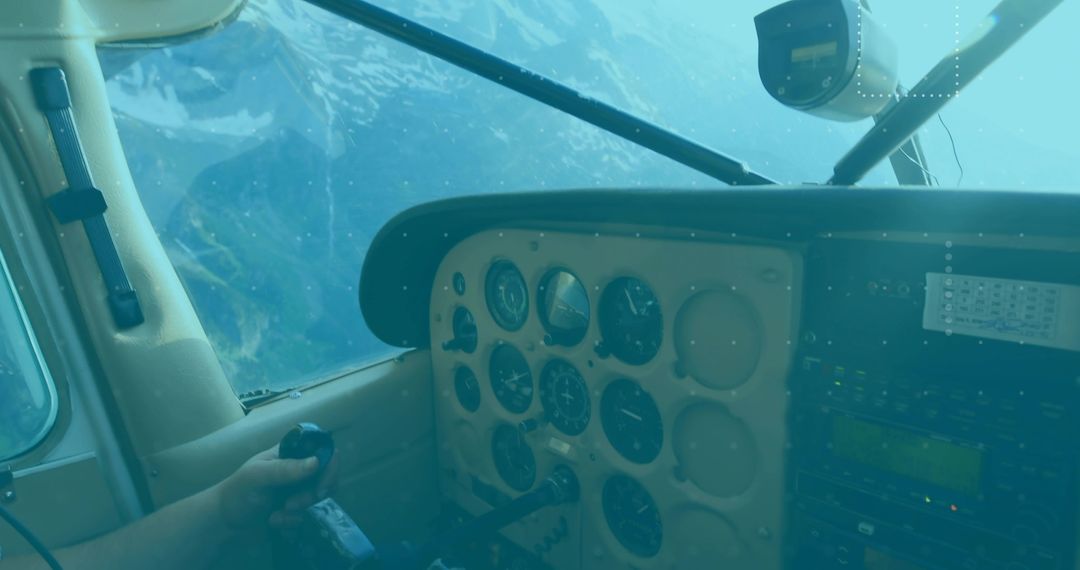 Pilot gripping yoke over snow-capped mountains in cockpit with analog instruments