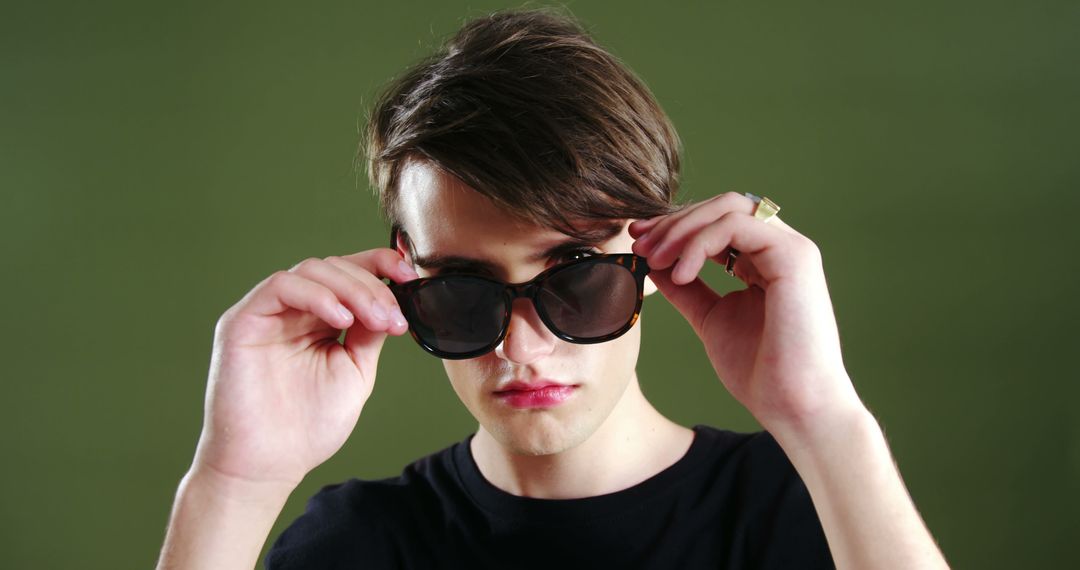 Young Man Adjusting Sunglasses Depicting Cool Confidence - Free Images, Stock Photos and Pictures on Pikwizard.com