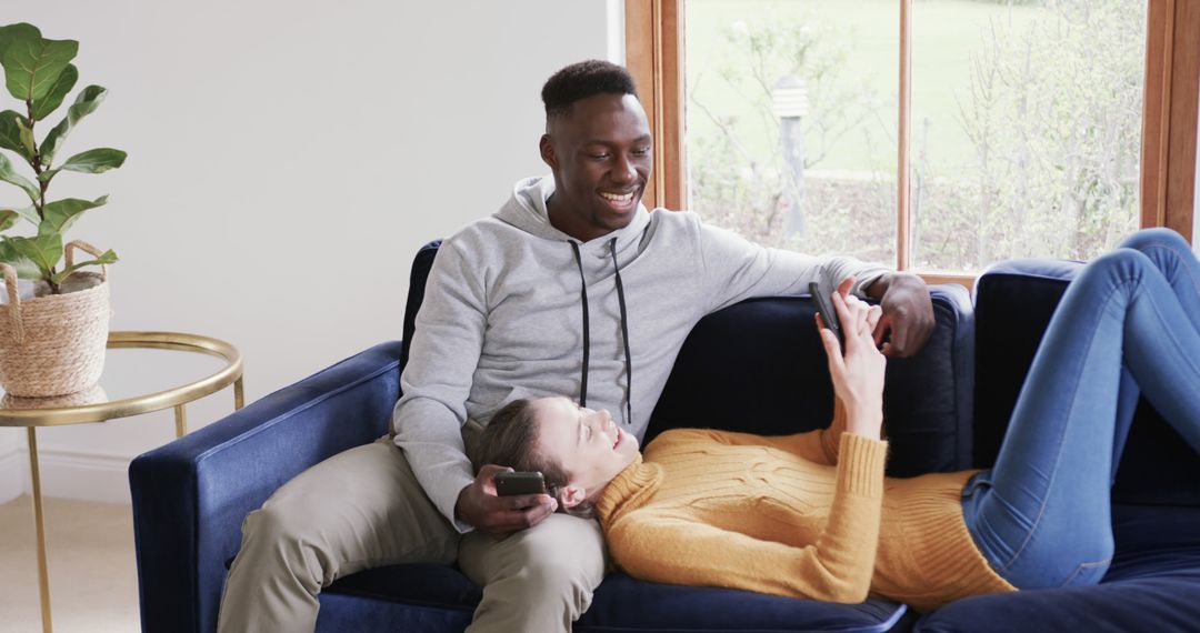 Interracial Couple Relaxing on Couch Browsing Devices Together - Free Images, Stock Photos and Pictures on Pikwizard.com