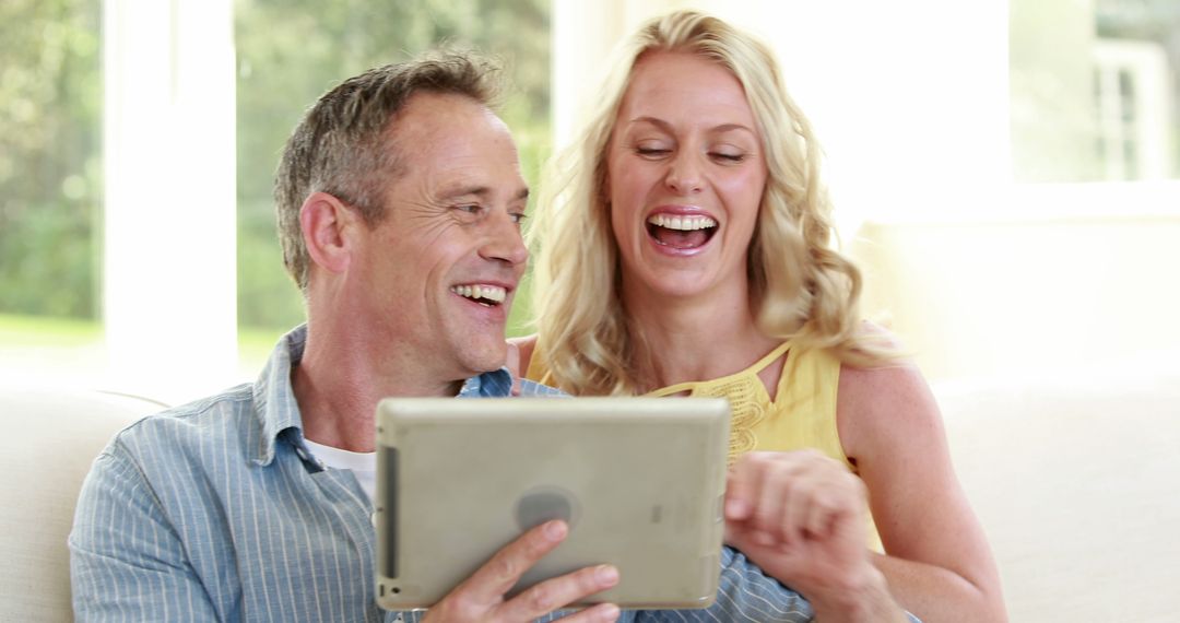 Joyful Couple Laughing Together Using Tablet at Home