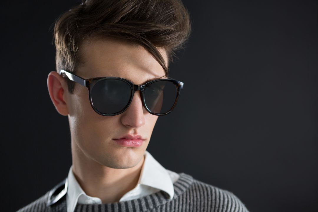 Androgynous man in sunglasses posing against black background - Free Images, Stock Photos and Pictures on Pikwizard.com