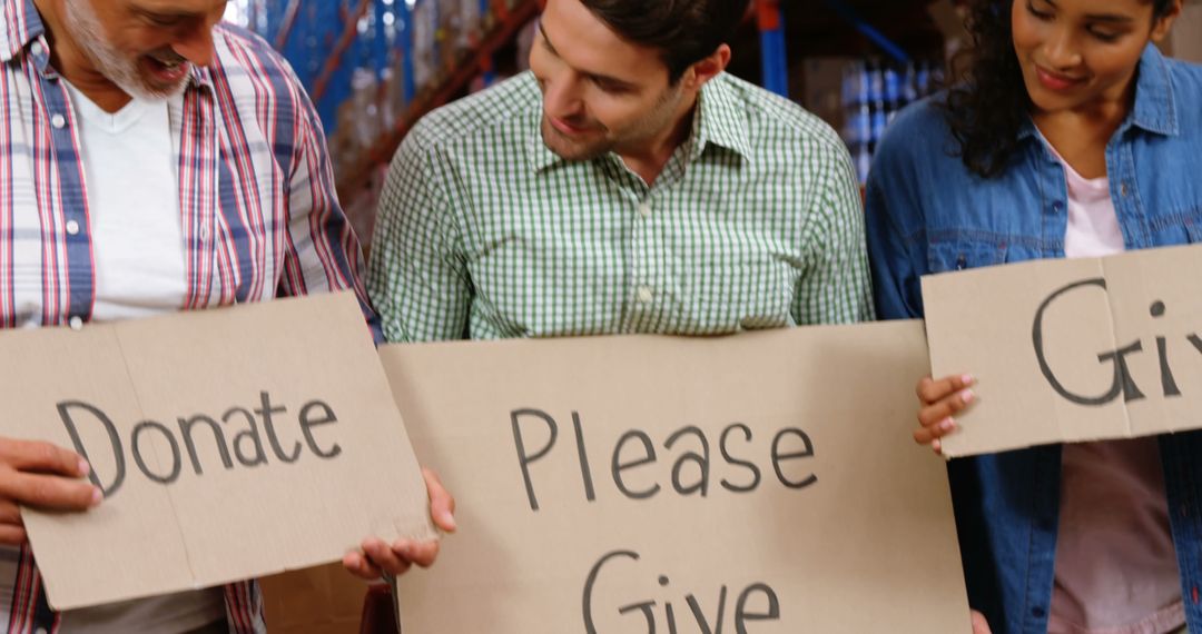 Diverse Volunteers Holding Donation Signs in Warehouse - Free Images, Stock Photos and Pictures on Pikwizard.com