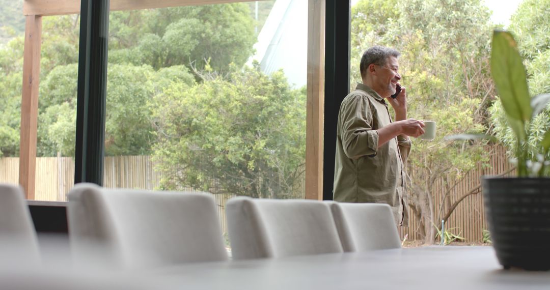 Senior Man Happing Talking on Phone by Window with Coffee - Free Images, Stock Photos and Pictures on Pikwizard.com