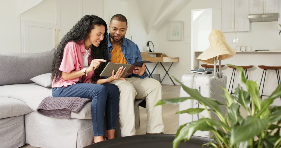 Couple Planning Vacation with Tablet and Passport on Couch