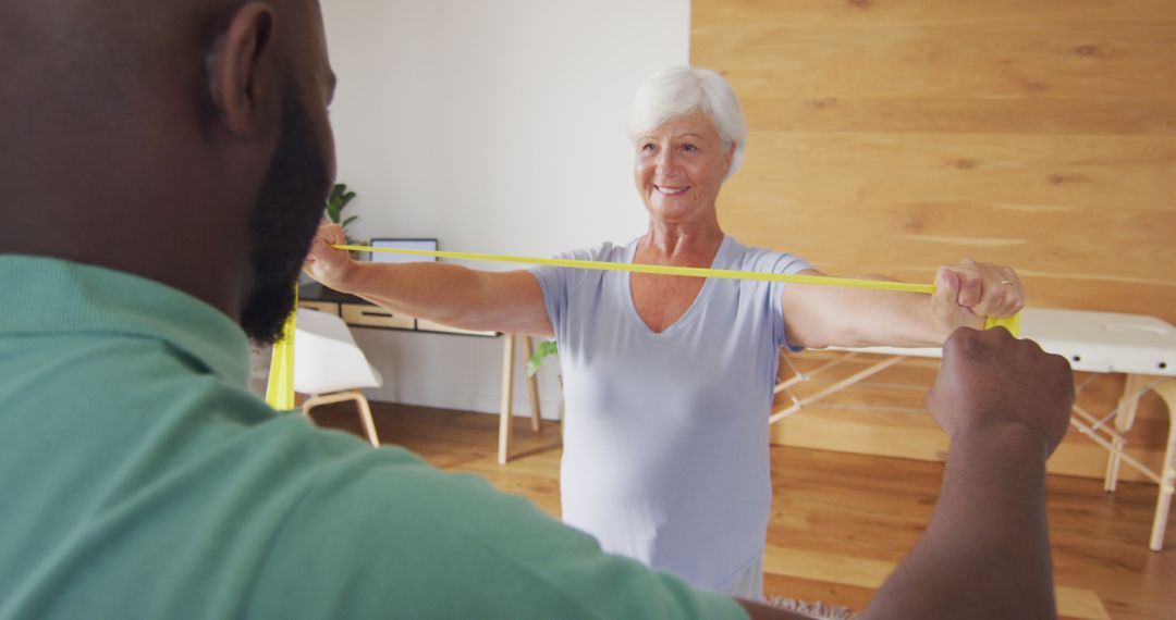 Senior Woman Exercising with Resistance Band under Trainer's Guidance - Free Images, Stock Photos and Pictures on Pikwizard.com