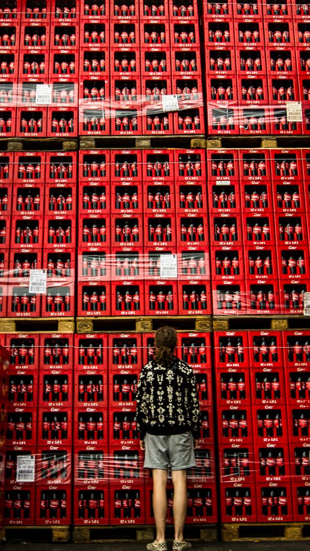 Person Standing in Front of Stacked Red Beverage Crates in Warehouse - Free Images, Stock Photos and Pictures on Pikwizard.com