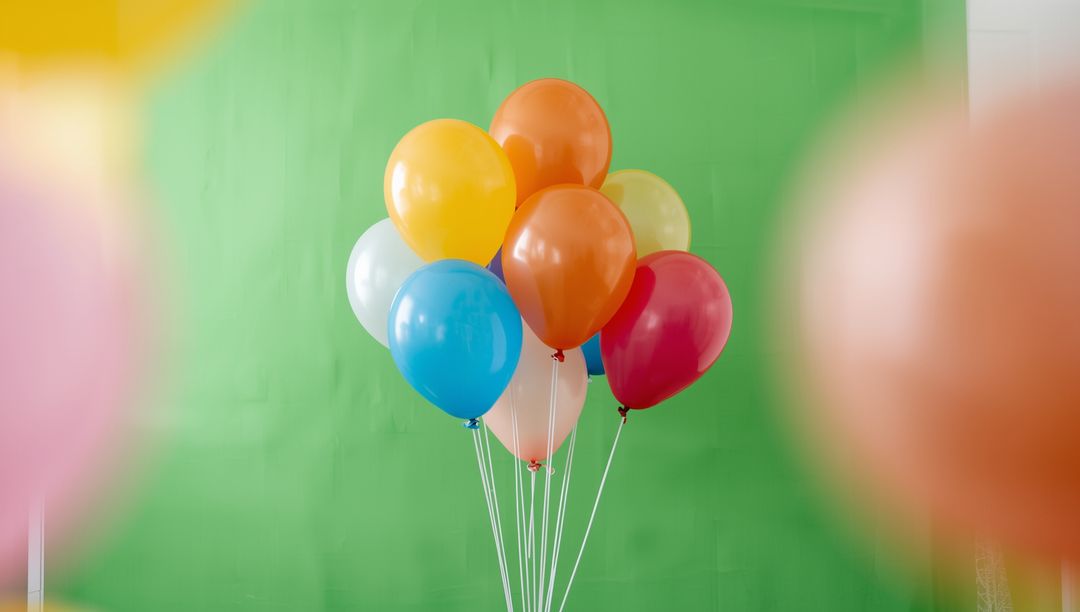 Colorful Helium Balloons Over Green Backdrop for Festive Celebrations