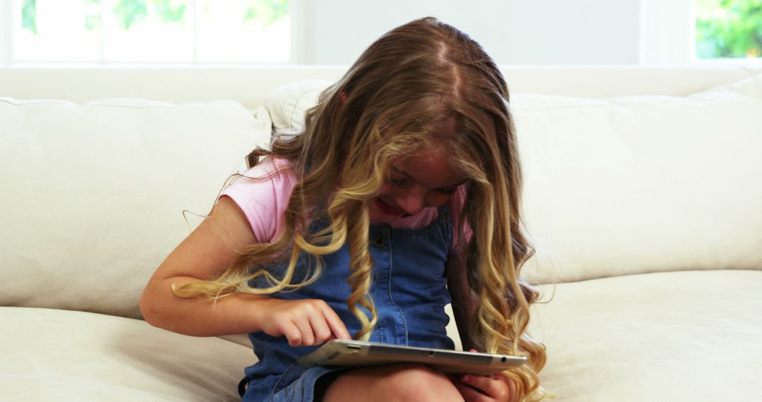 Young Girl Using Tablet on Couch Embracing Digital Technology - Free Images, Stock Photos and Pictures on Pikwizard.com