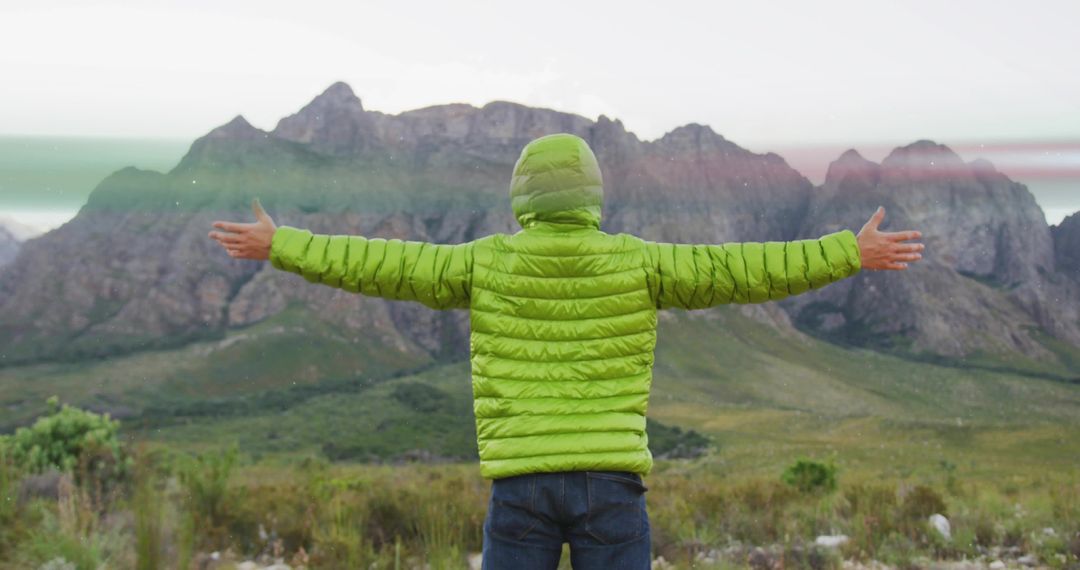 Hiker Embracing Nature Standing in Foothills Against Breathtaking Mountain Range