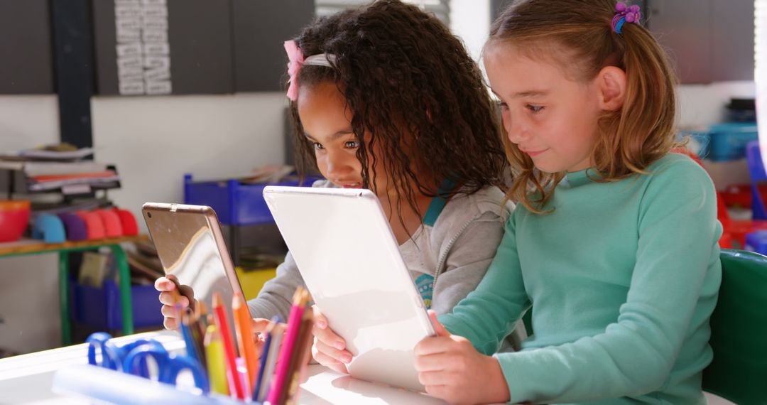 Two Young Schoolgirls Using Tablets Collaboratively