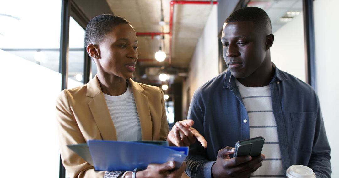 Colleagues Collaborating While Walking in Modern Office Corridor