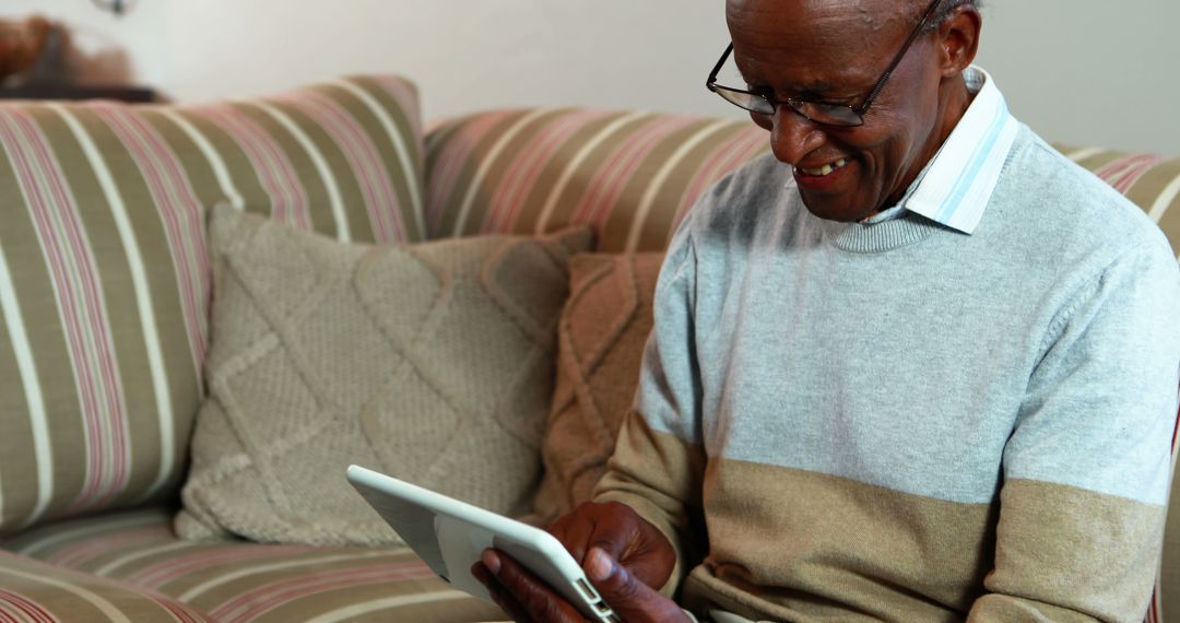 Happy Elderly Man Using Tablet on Couch - Free Images, Stock Photos and Pictures on Pikwizard.com