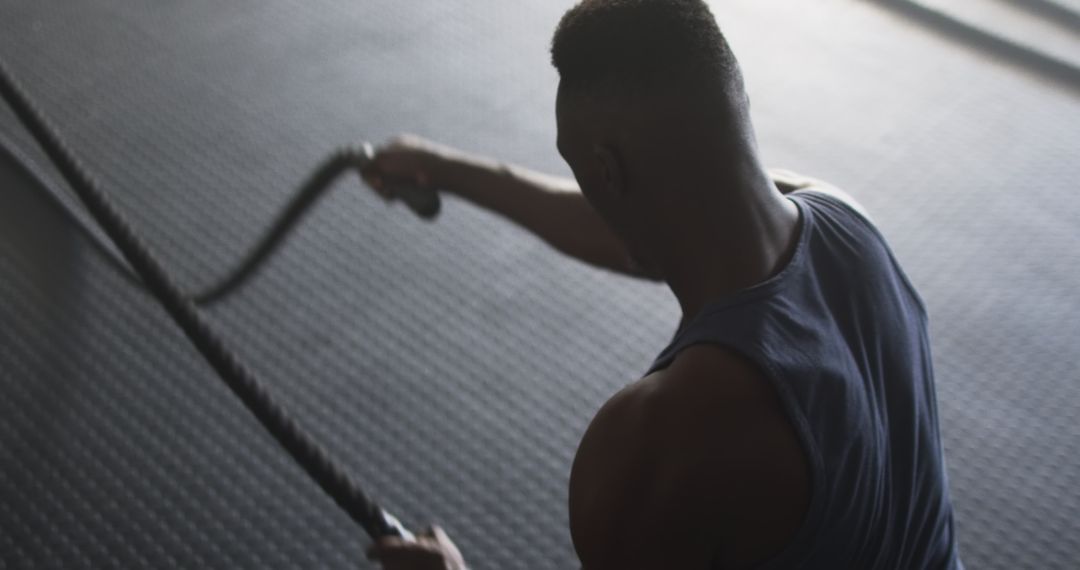 Focused Man Engaging in Intense Workout with Battle Ropes at Gym
