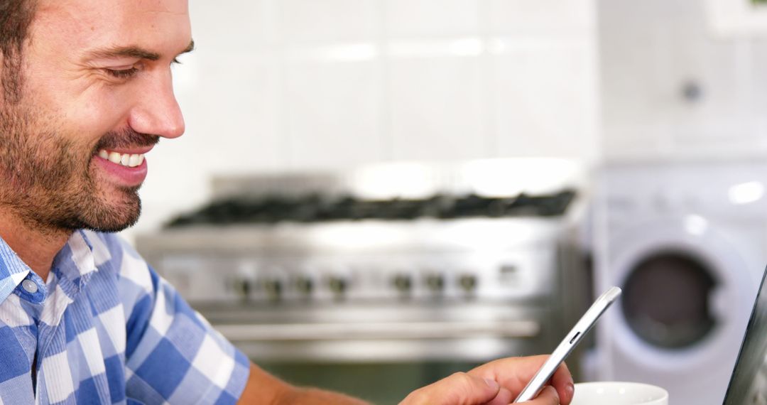 Smiling Man Using Smartphone in Kitchen - Free Images, Stock Photos and Pictures on Pikwizard.com