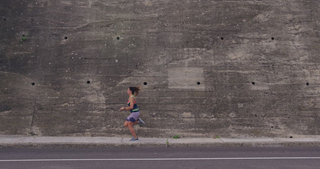 Woman Jogging Along Urban Concrete Wall for Fitness - Free Images, Stock Photos and Pictures on Pikwizard.com