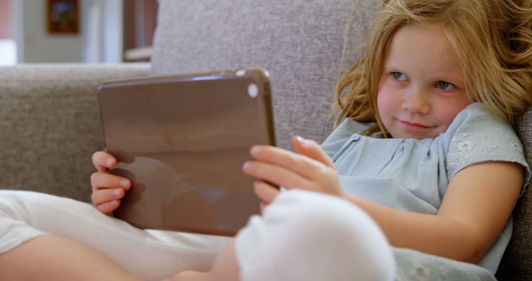 Young Girl Relaxing on Sofa with Tablet - Free Images, Stock Photos and Pictures on Pikwizard.com