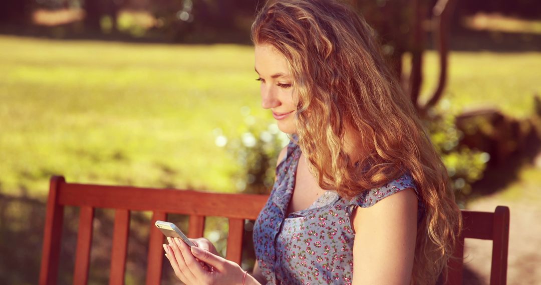 Woman with Long Curly Hair Using Mobile Phone on Park Bench - Free Images, Stock Photos and Pictures on Pikwizard.com