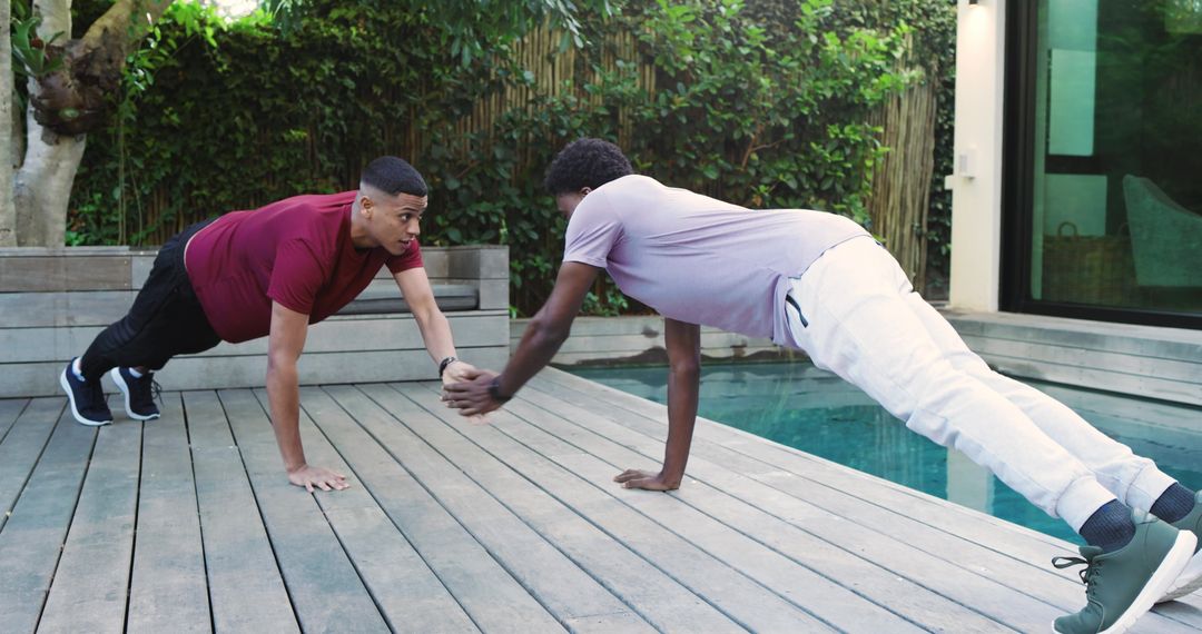 Diverse Friends Engaging in Plank Handshake by Poolside