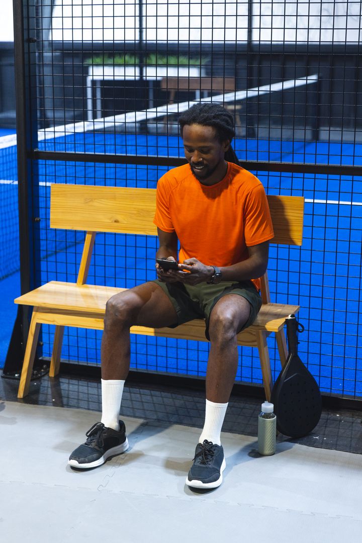 Padel Enthusiast Relaxed on Bench Checking Smartphone