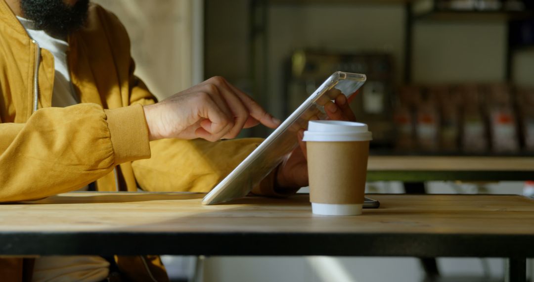 Person Browsing Tablet with Coffee Cup in Café - Free Images, Stock Photos and Pictures on Pikwizard.com