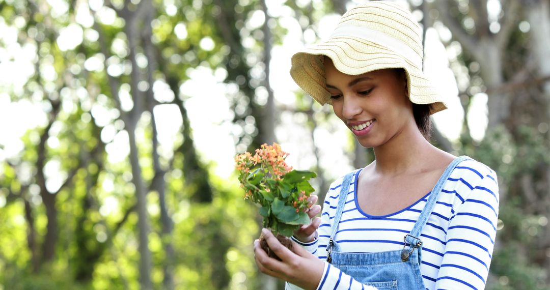Portrait of smiling biracial woman holding plant in garden with copy space - Free Images, Stock Photos and Pictures on Pikwizard.com