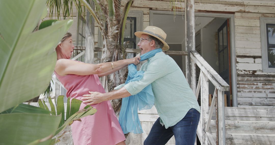 Elderly Man and Woman Playing Outside Rustic House in Tropics - Free Images, Stock Photos and Pictures on Pikwizard.com