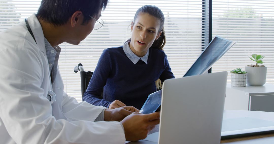 Doctor Consulting Patient Analyzing X-ray in Modern Medical Office - Free Images, Stock Photos and Pictures on Pikwizard.com