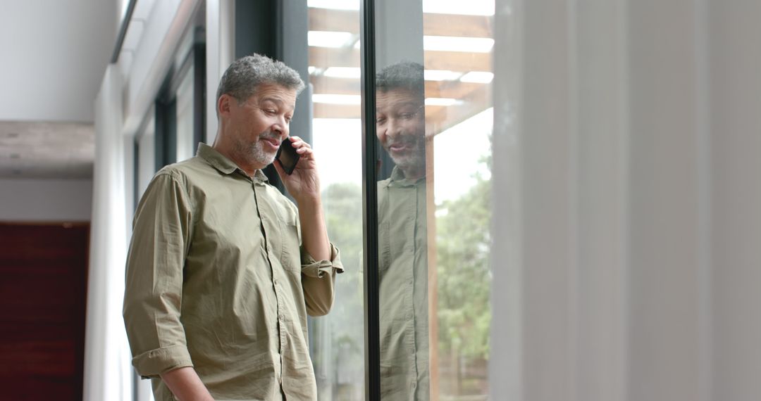 Mature Man Talking on Phone at Home Near Window - Free Images, Stock Photos and Pictures on Pikwizard.com