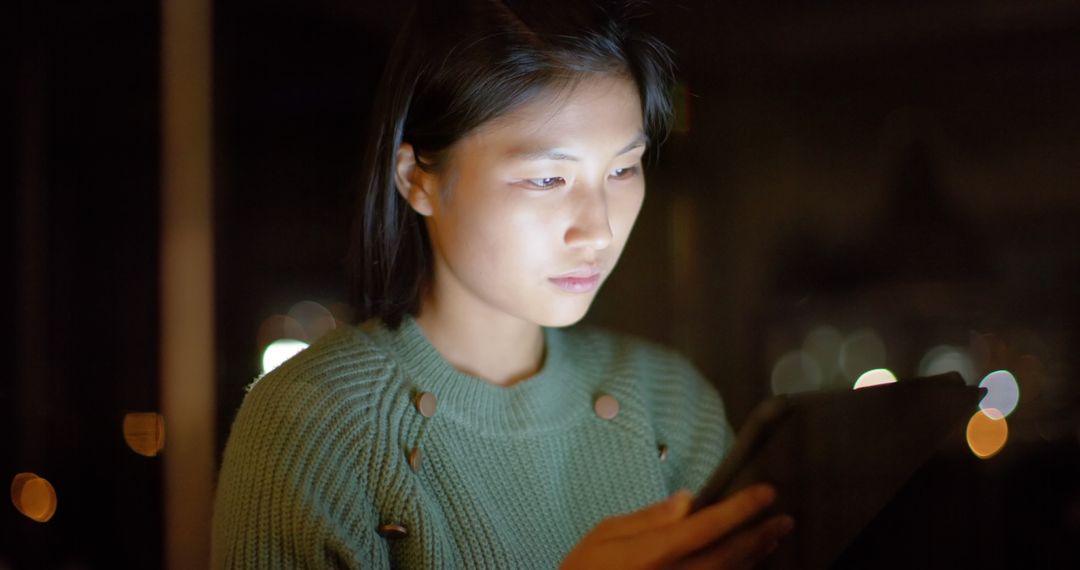 Young Woman Using Tablet at Night with Focused Expression - Free Images, Stock Photos and Pictures on Pikwizard.com