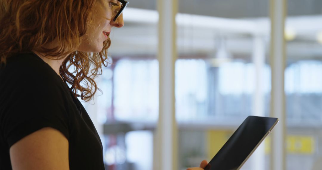 Young Woman Analyzing Data on Tablet in Office Environment