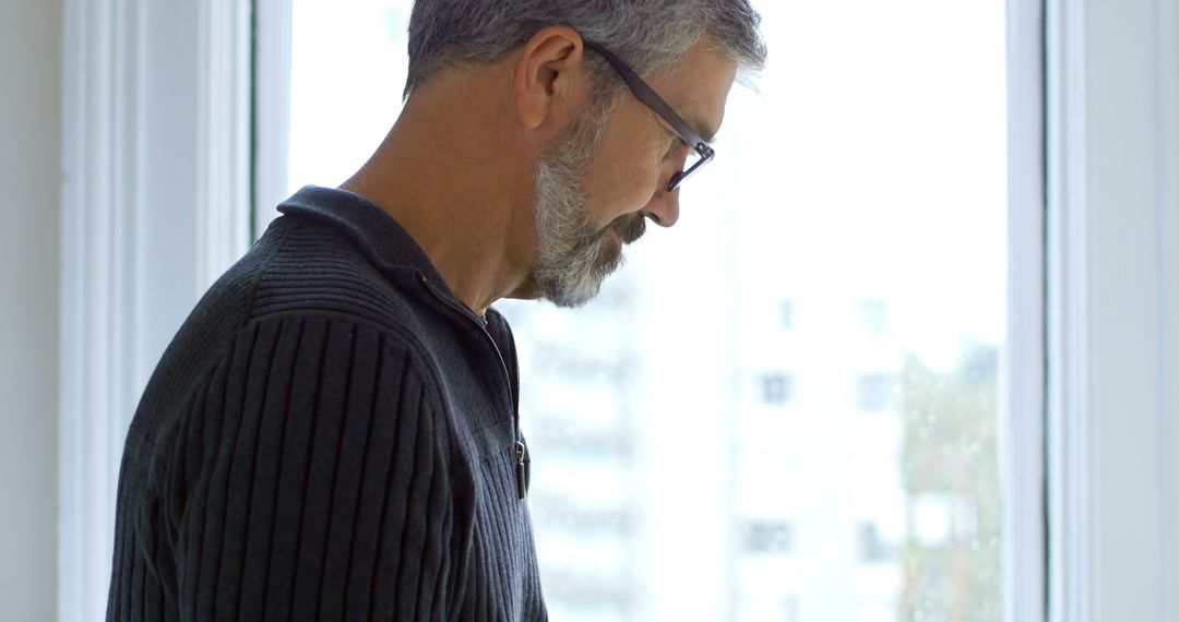 Middle-aged Man Reflects by Window with Contemplative Pose