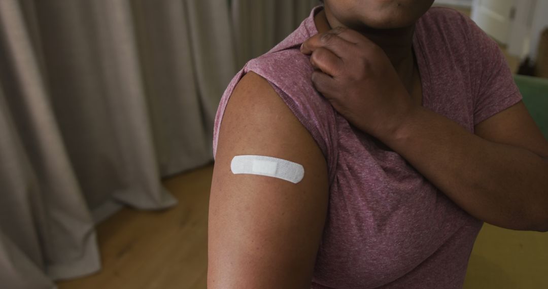 Person showing arm with adhesive bandage indicating recent vaccination - Free Images, Stock Photos and Pictures on Pikwizard.com