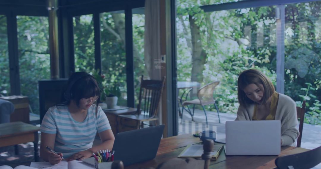 Asian Mother and Daughter Working Together on Laptops at Home