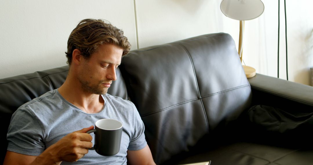 Man Reading Book and Drinking Coffee on Leather Sofa - Free Images, Stock Photos and Pictures on Pikwizard.com