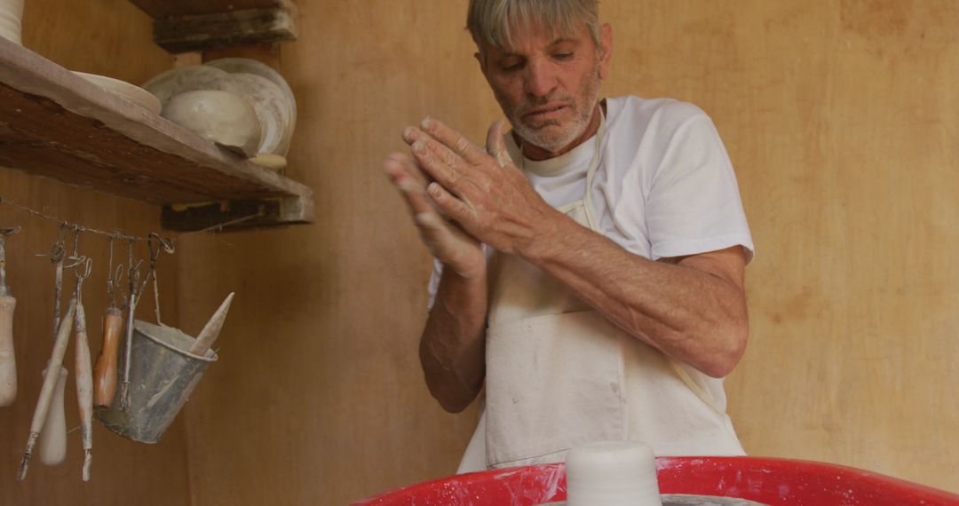 Senior Man Engaged in Pottery Handcrafting in Workshop